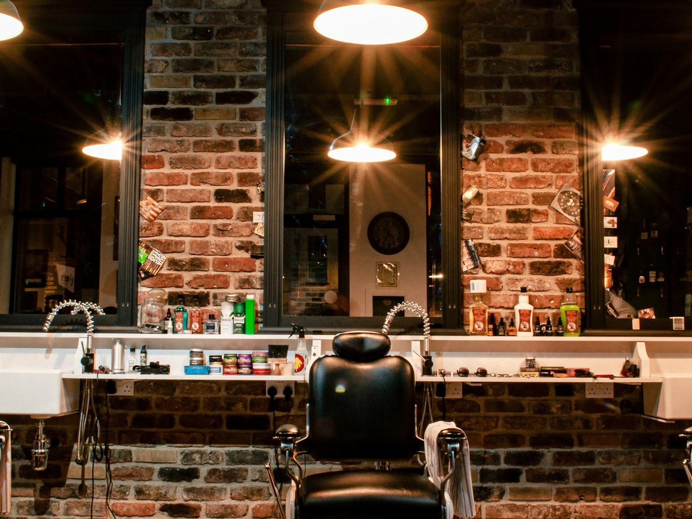 The row of barber's chairs and the mirrors along the brick wall, under the shop's pendant lamps