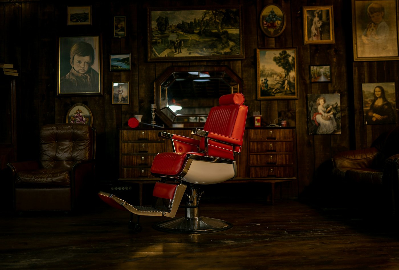 The red chair in the back room, the wall behind it hung with framed pictures